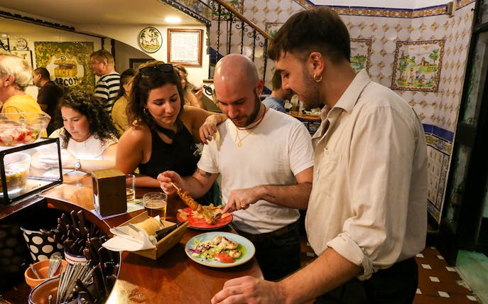 Group enjoying tapas in a traditional Triana bar during a guided tour.