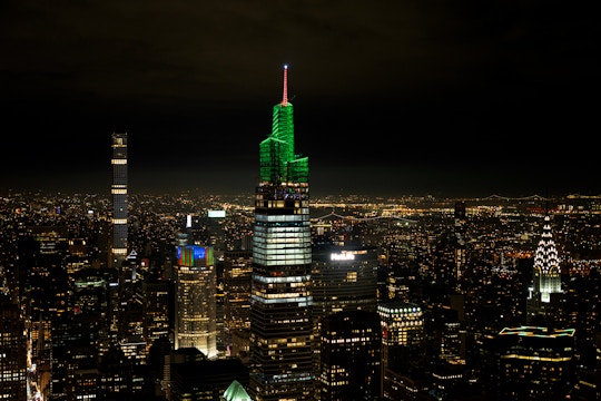 Summit One Vanderbilt illuminated at night with Christmas lights, New York City skyline in background.