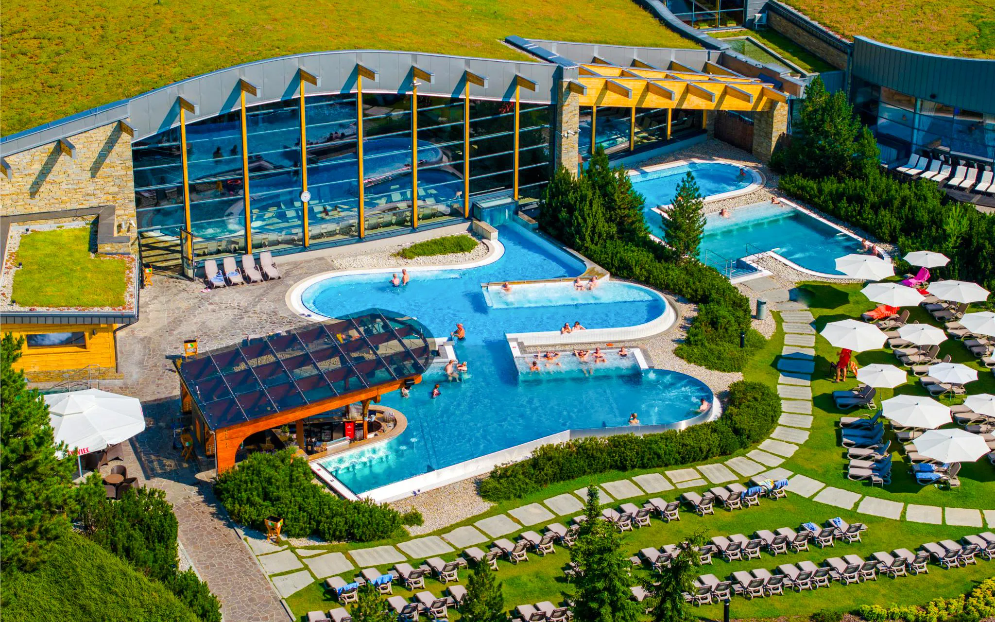 Thermal pools at Terma Bania in Białka Tatrzańska, surrounded by greenery and lounge chairs.