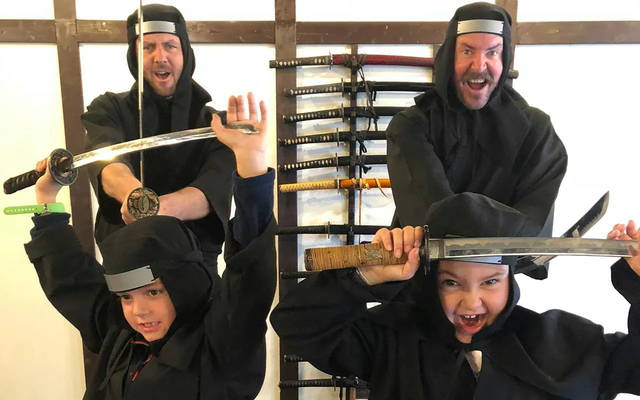 Participants in ninja attire holding swords at Osaka Ninja Workshop.