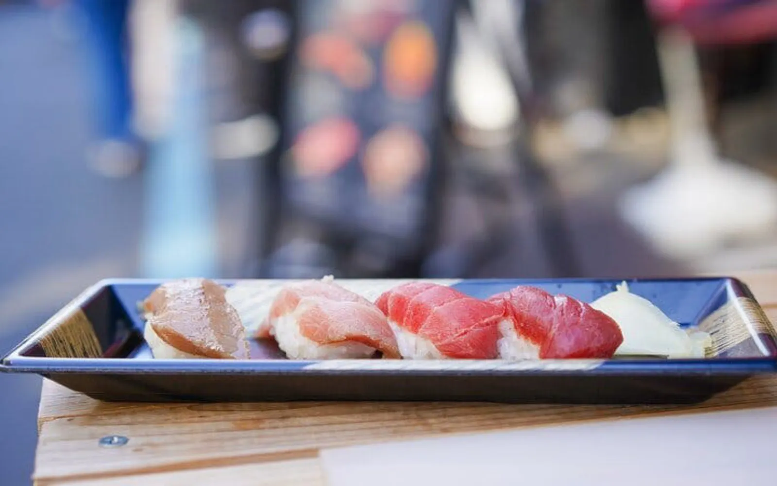 Sushi platter at Tsukiji Market, Tokyo, featuring assorted nigiri on a black tray.