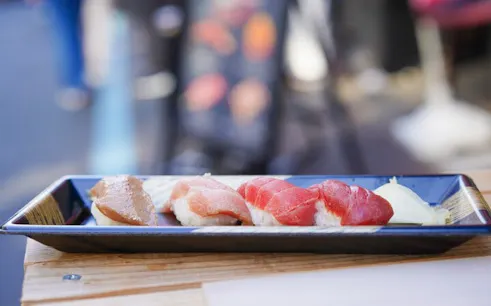 Sushi platter at Tsukiji Market, Tokyo, featuring assorted nigiri on a black tray.