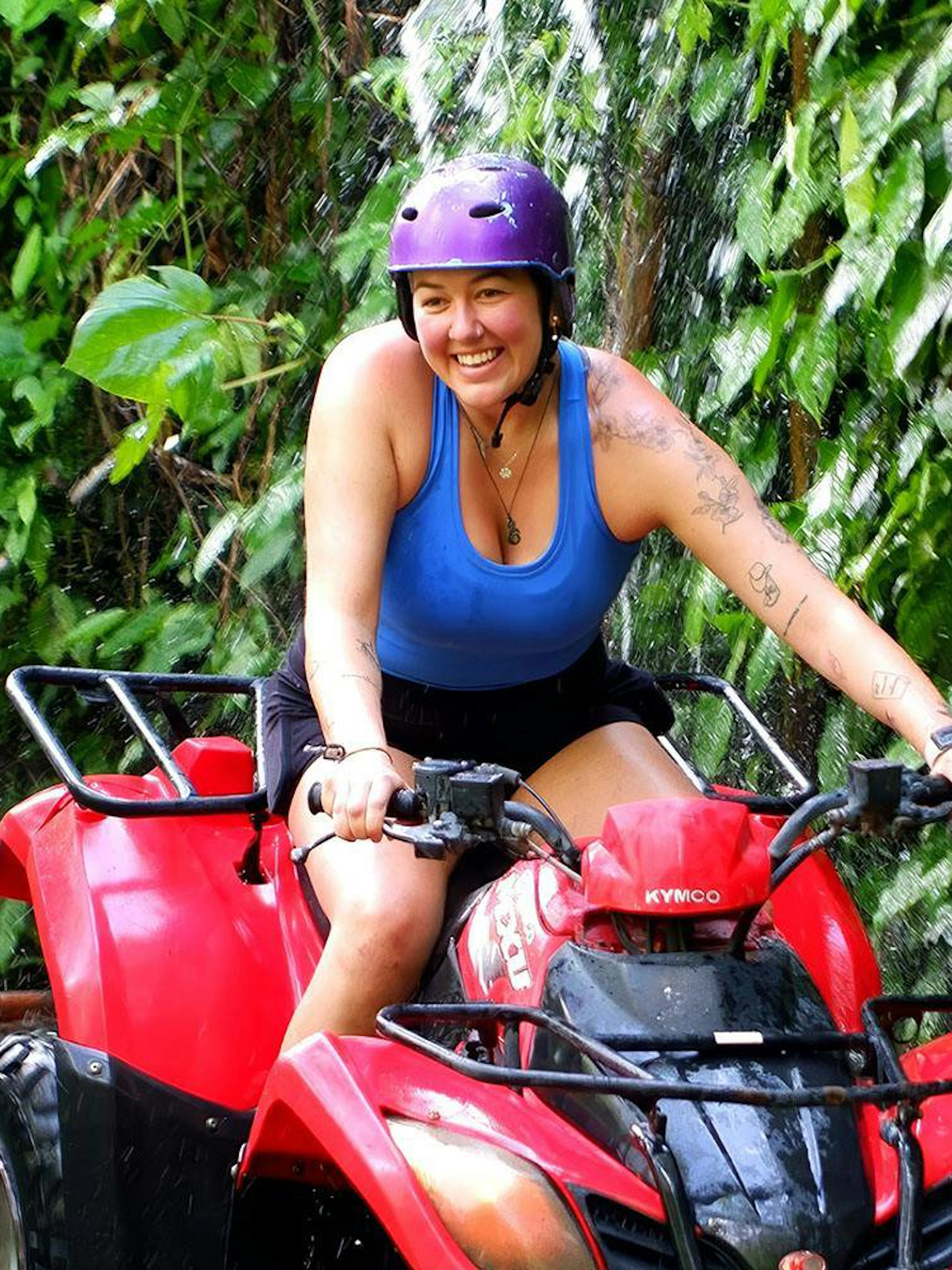 Tourist riding a red quad bike through lush greenery in Bali.