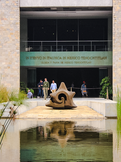 Entrance of the Anthropology Museum in Mexico City with a stone sculpture and reflecting pool.