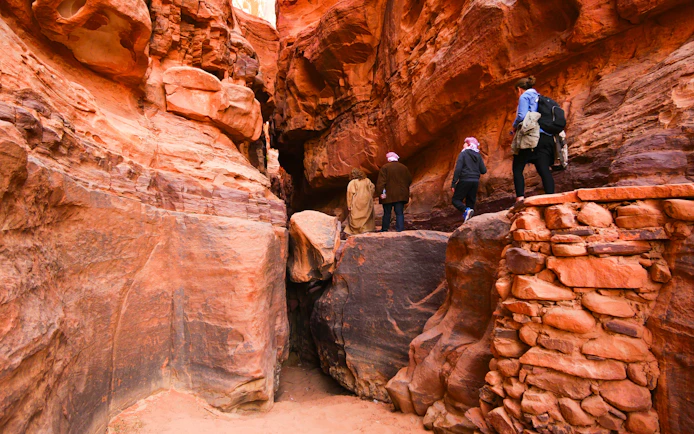 Hikers exploring a narrow canyon in Wadi Rum, Jordan.