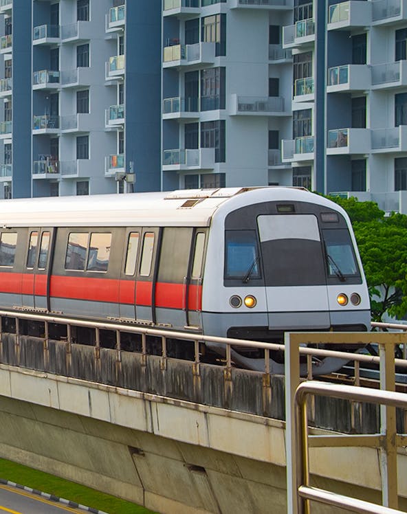 Metro train on elevated track with buildings in Singapore.