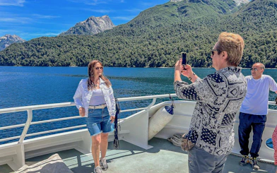 Travelers on a boat deck enjoying views of Nahuel Huapi Lake and surrounding mountains.
