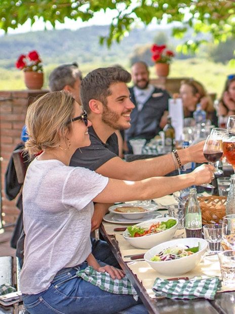 Lunch gathering during Montserrat monastery tour with people toasting at an outdoor table.