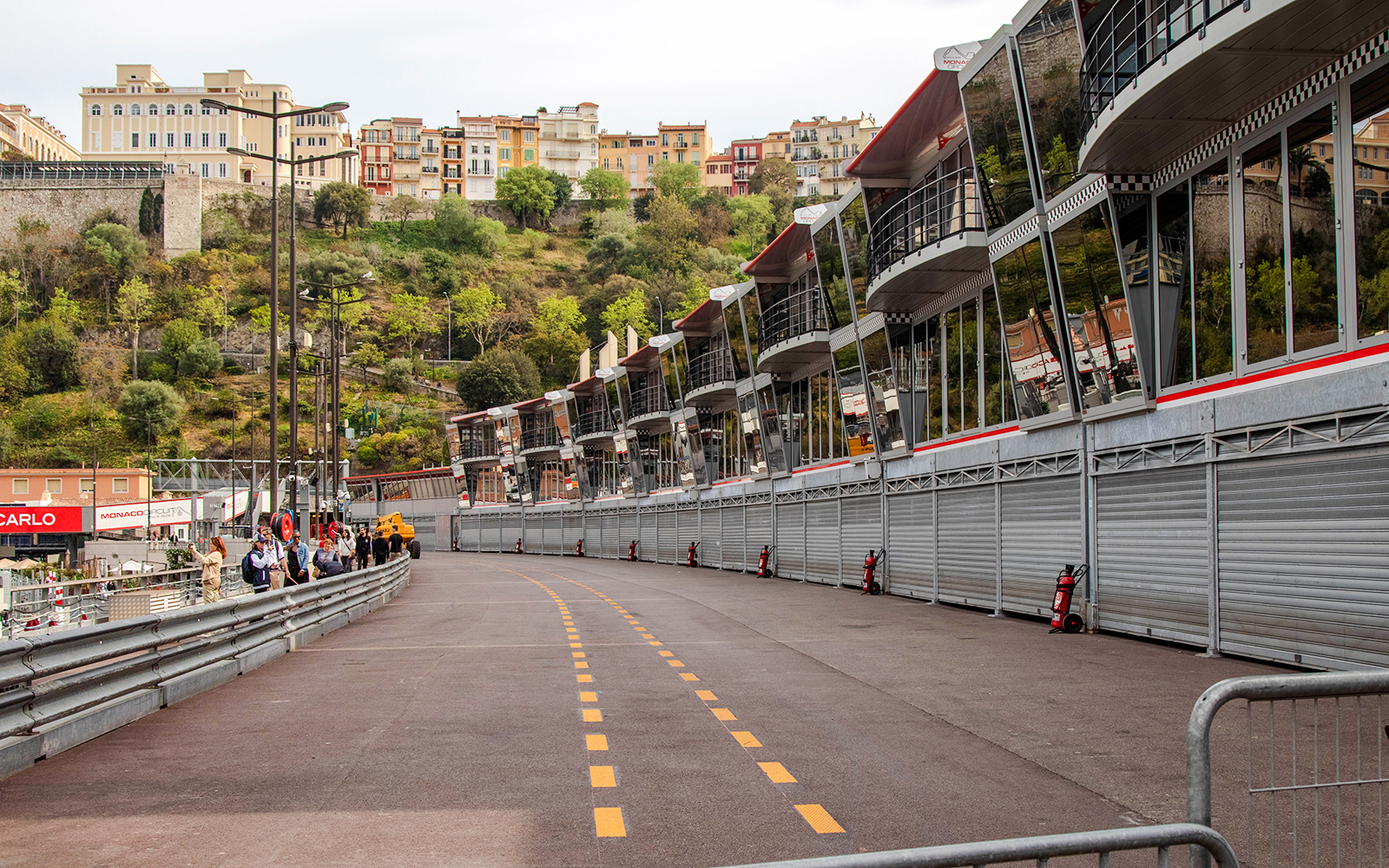 Monaco Formula 1 pit lane with grandstands and hillside buildings in the background.