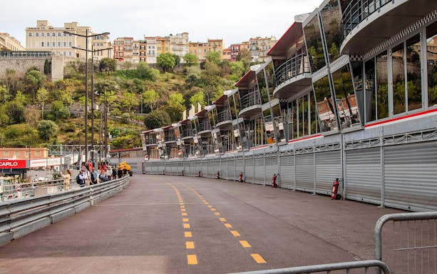 Monaco Formula 1 pit lane with grandstands and hillside buildings in the background.