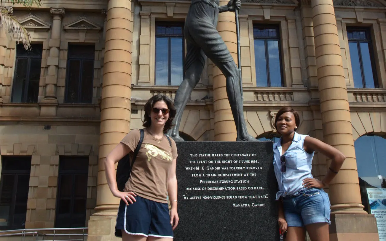 Statue of Gandhi at Pietermaritzburg station, South Africa, with two visitors.