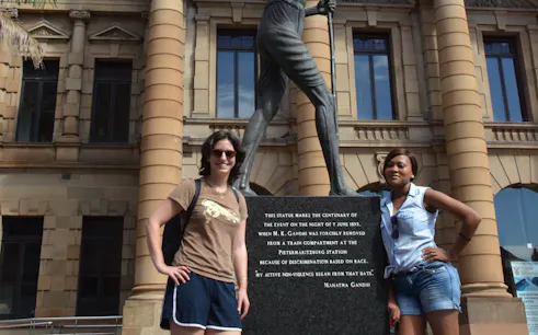 Statue of Gandhi at Pietermaritzburg station, South Africa, with two visitors.
