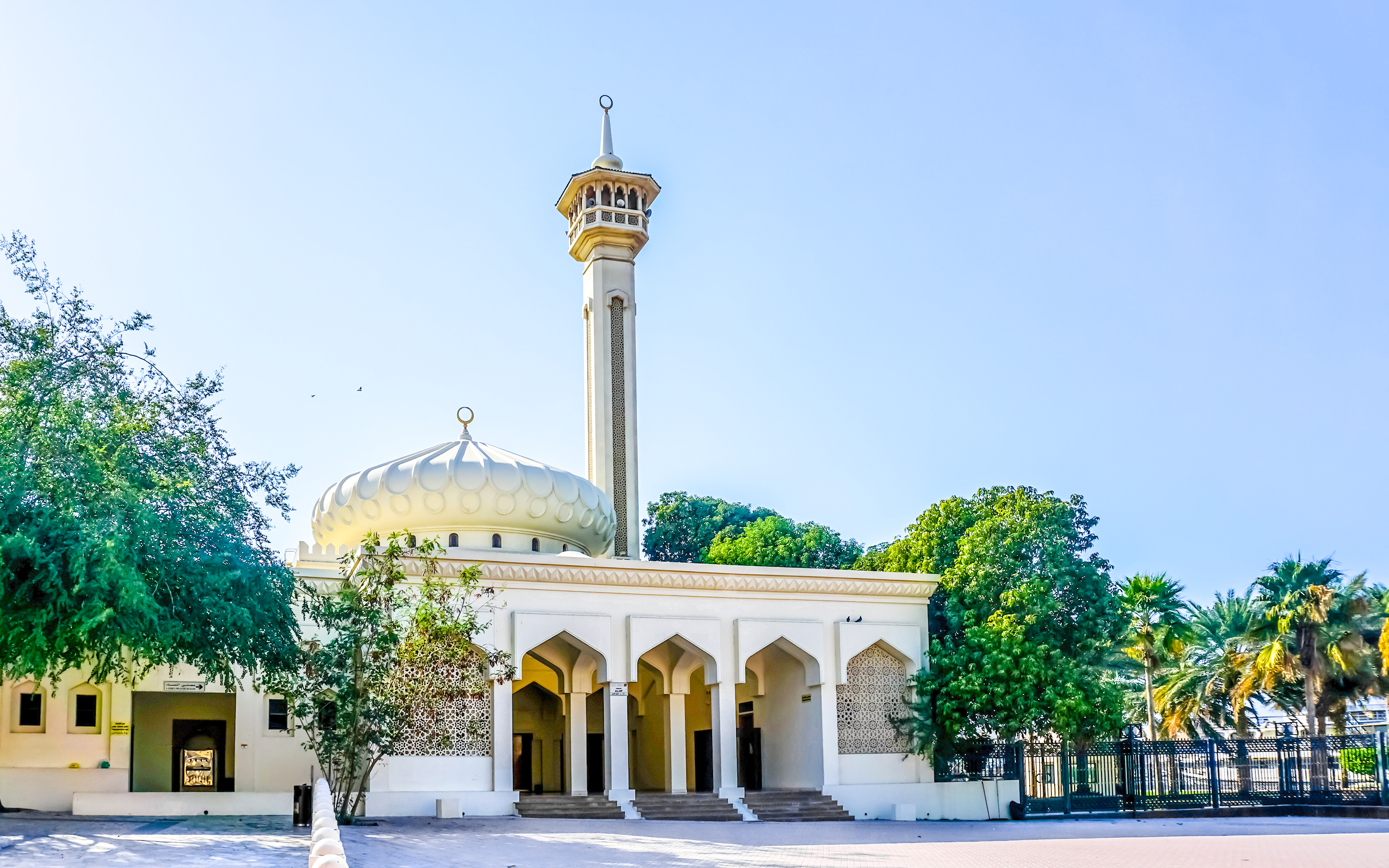 Al Farooq Mosque in Dubai with its minaret and arched entrance surrounded by trees.