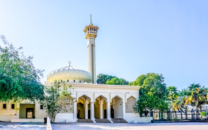 Al Farooq Mosque in Dubai with its minaret and arched entrance surrounded by trees.