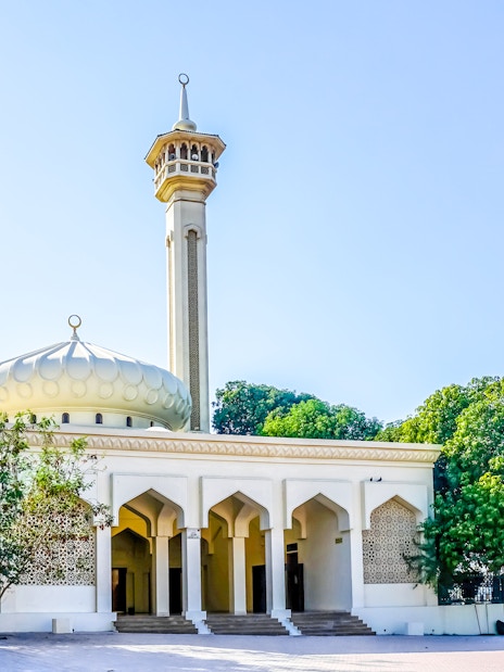 Al Farooq Mosque in Dubai with its minaret and arched entrance surrounded by trees.
