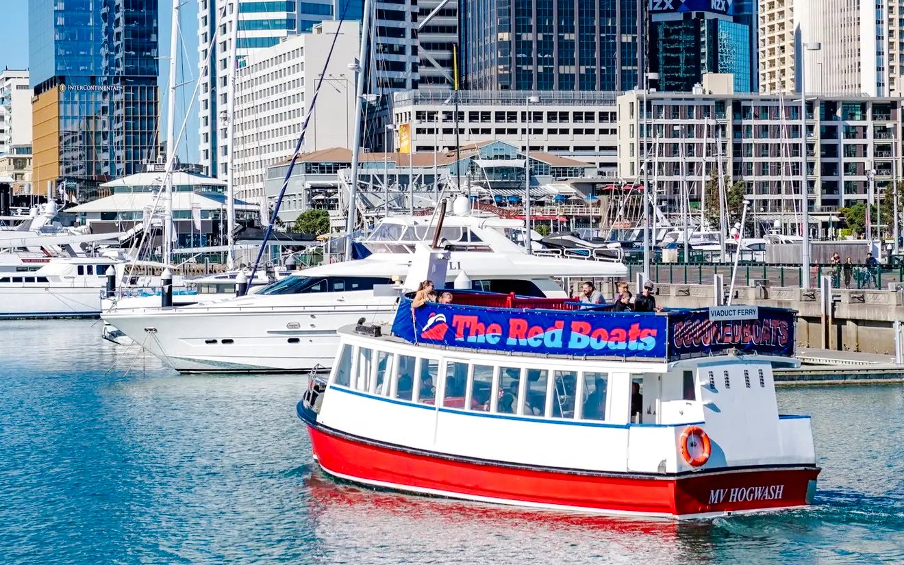 Auckland harbour cruise boat with passengers and city skyline in the background.