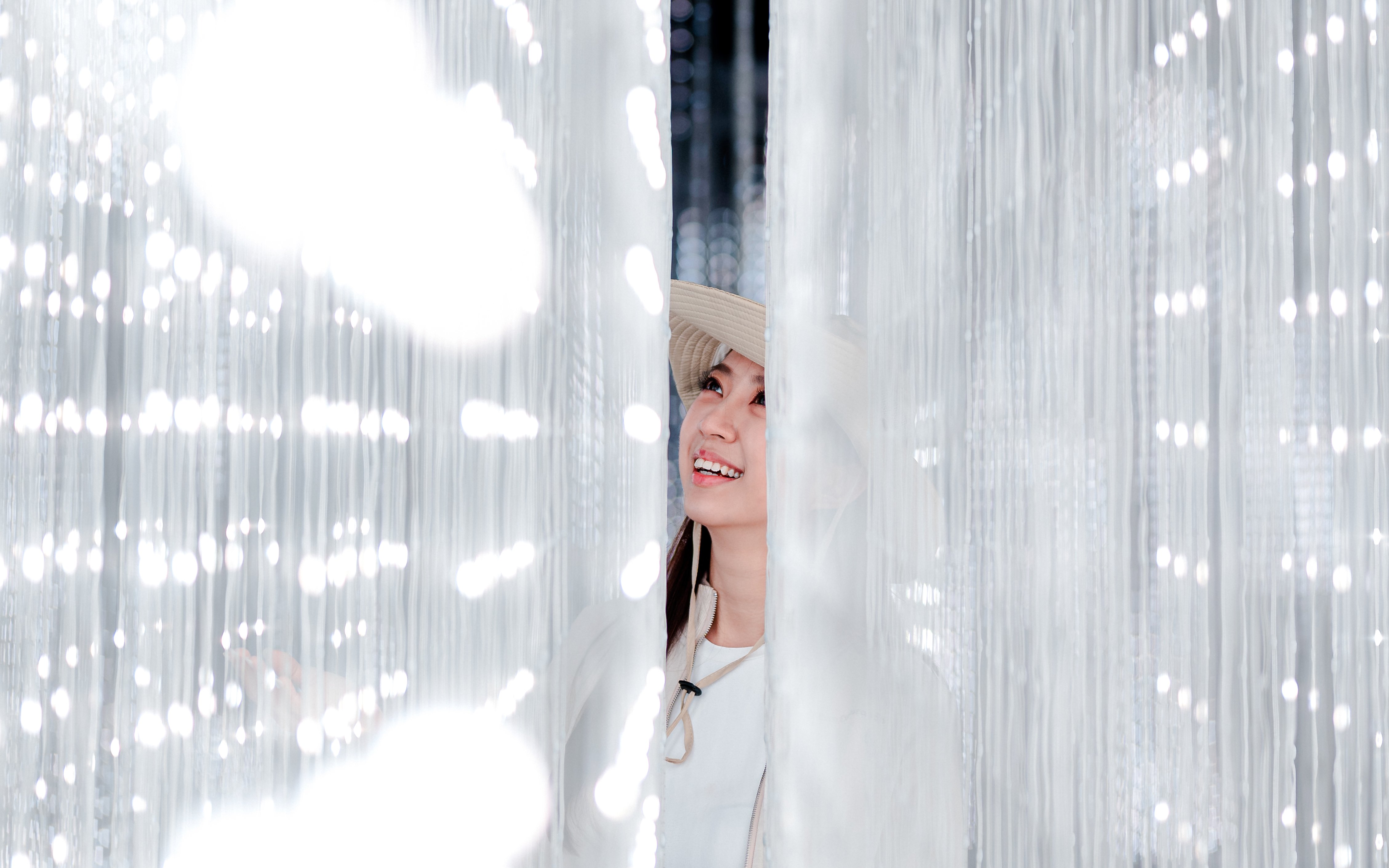 Lady smiling amid colorful lights at Enchanted Forest exhibit.