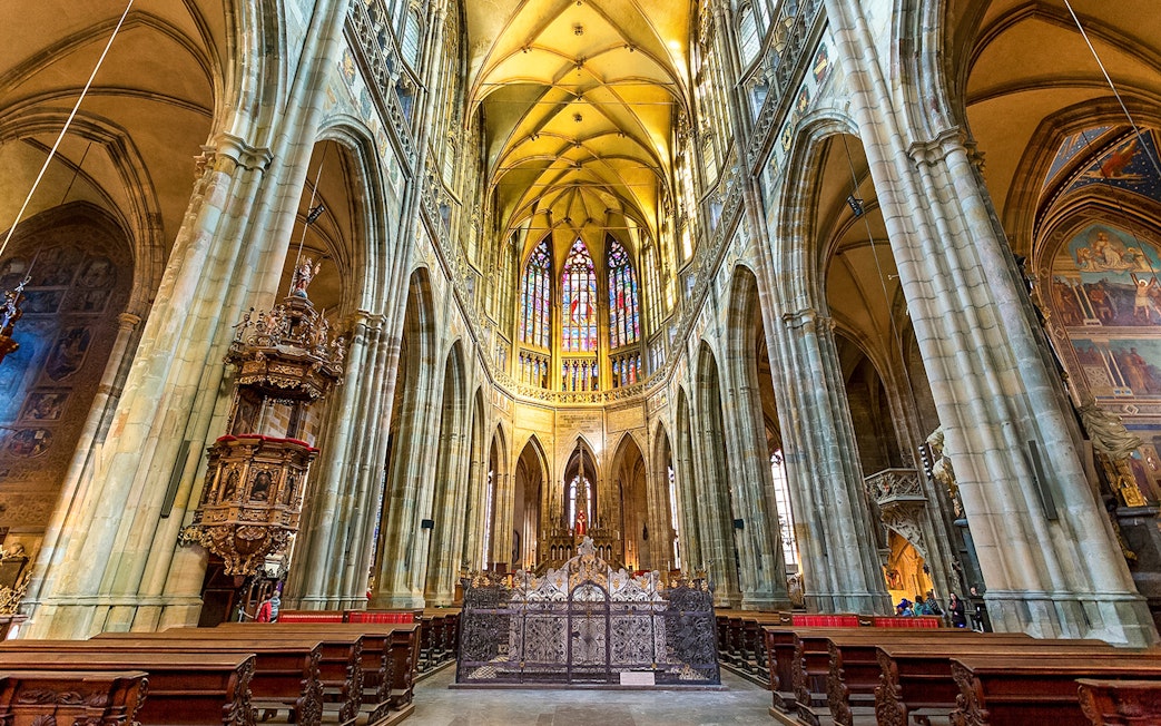 Gothic interior of Saint Vitus Cathedral with stained glass windows and vaulted ceilings.