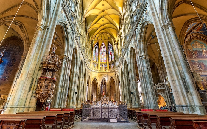 Gothic interior of Saint Vitus Cathedral with stained glass windows and vaulted ceilings.