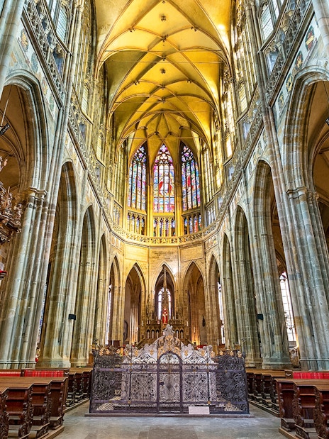 Gothic interior of Saint Vitus Cathedral with stained glass windows and vaulted ceilings.