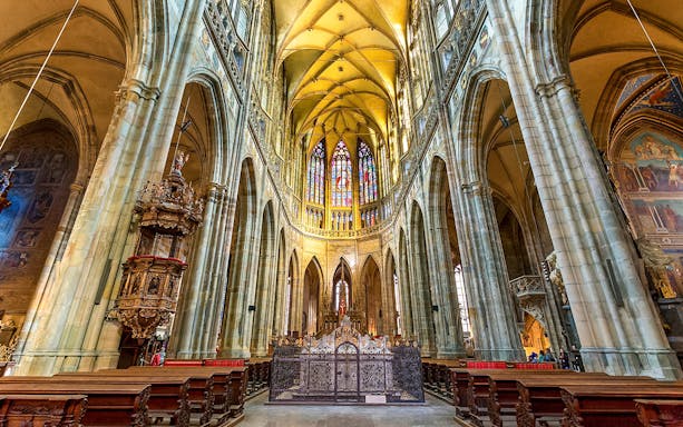 Gothic interior of Saint Vitus Cathedral with stained glass windows and vaulted ceilings.