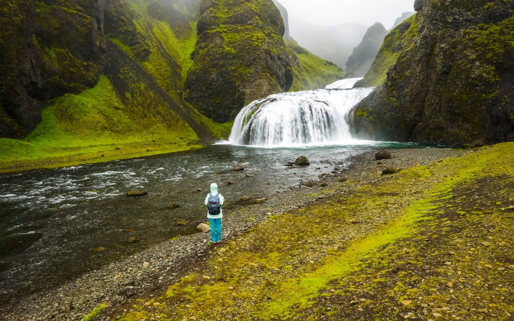 Woman standing near Stjornarfoss waterfall in Iceland.