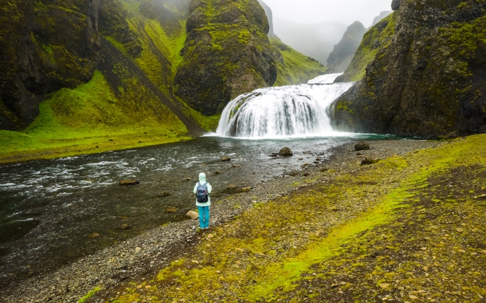 Woman standing near Stjornarfoss waterfall in Iceland.