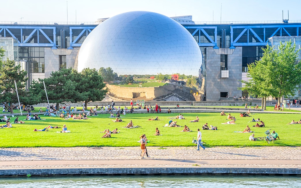 Visitors relaxing on the lawn in front of the Geode at the Science and Industry Museum, Paris.