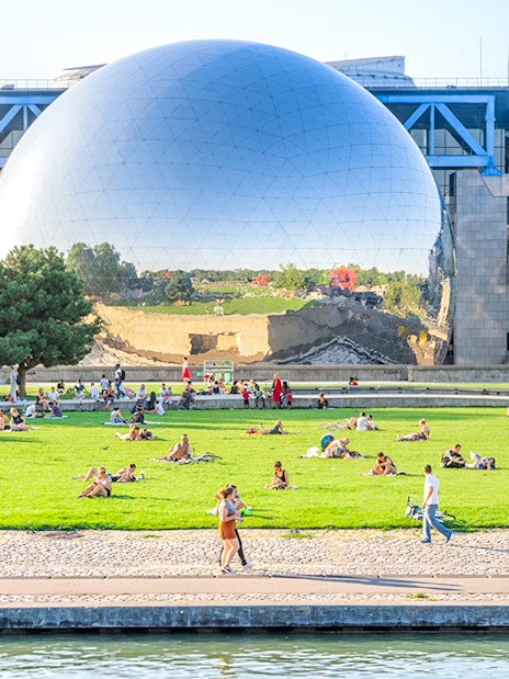 Visitors relaxing on the lawn in front of the Geode at the Science and Industry Museum, Paris.