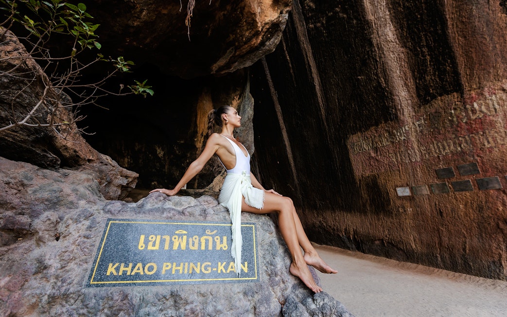 Khao Phing Kan rock formation with a person sitting on a stone ledge.