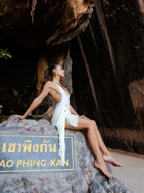 Khao Phing Kan rock formation with a person sitting on a stone ledge.