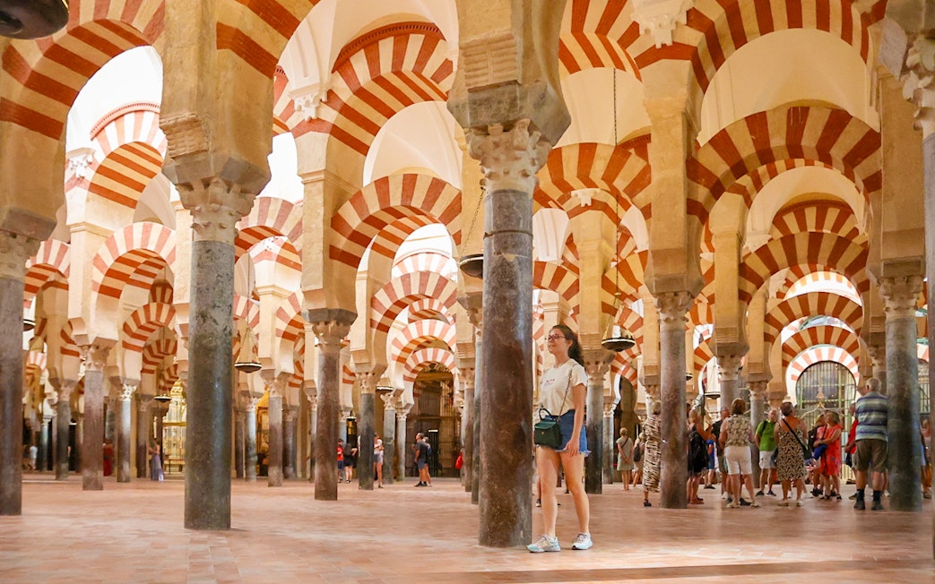 Women walking inside the Mosque-Cathedral of Cordoba, Spain, with iconic arches.