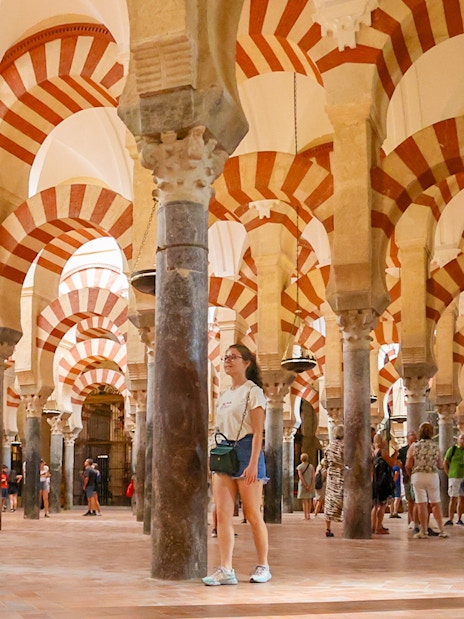 Women walking inside the Mosque-Cathedral of Cordoba, Spain, with iconic arches.