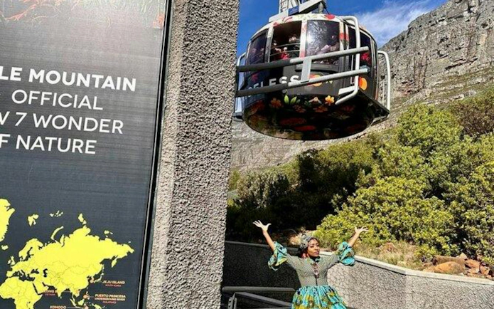 Table Mountain cable car ascending with a person standing below, Cape Town.