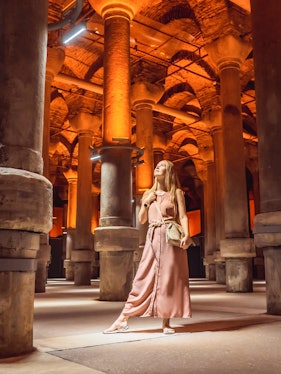 Visitor exploring the illuminated columns of the Basilica Cistern in Istanbul.
