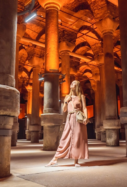 Visitor exploring the illuminated columns of the Basilica Cistern in Istanbul.