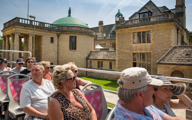 Tourists on an open-top bus during a 24/48-Hr Hop-On Hop-Off Tour of Oxford, passing historic buildings.