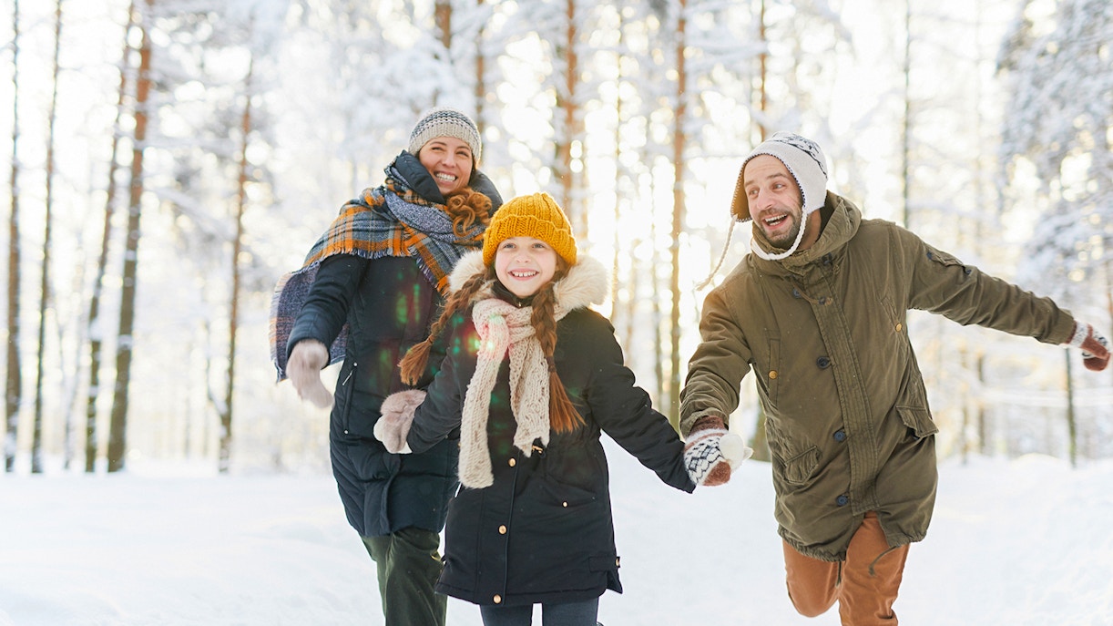 Family hiking near snow-covered Niagara Falls in winter.