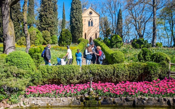 Tourists exploring Hermitage of Laura at Parco Giardino Sigurtà with vibrant gardens.