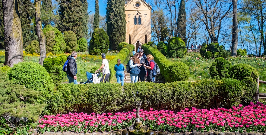 Tourists exploring Hermitage of Laura at Parco Giardino Sigurtà with vibrant gardens.