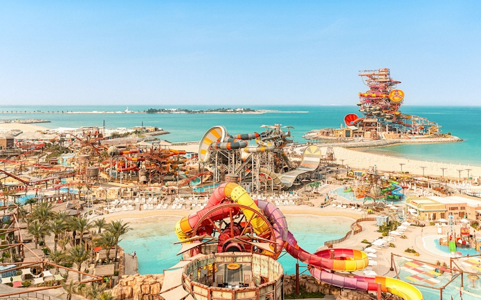 Aerial view of colorful water slides and pools at Meryal Waterpark by the sea.