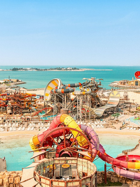 Aerial view of colorful water slides and pools at Meryal Waterpark by the sea.
