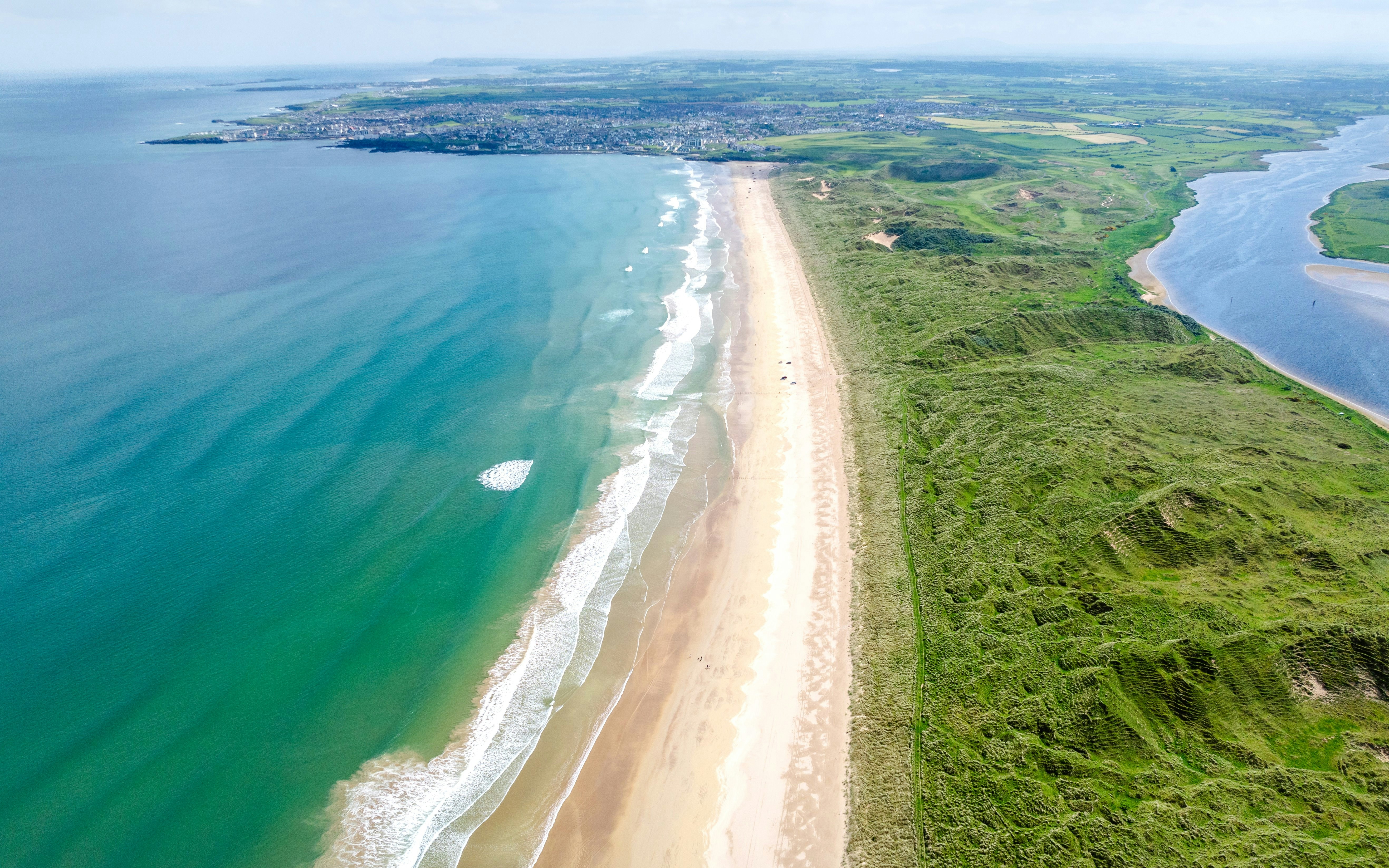 Aerial view of Portstewart Strand with sandy beach and green dunes in Northern Ireland.