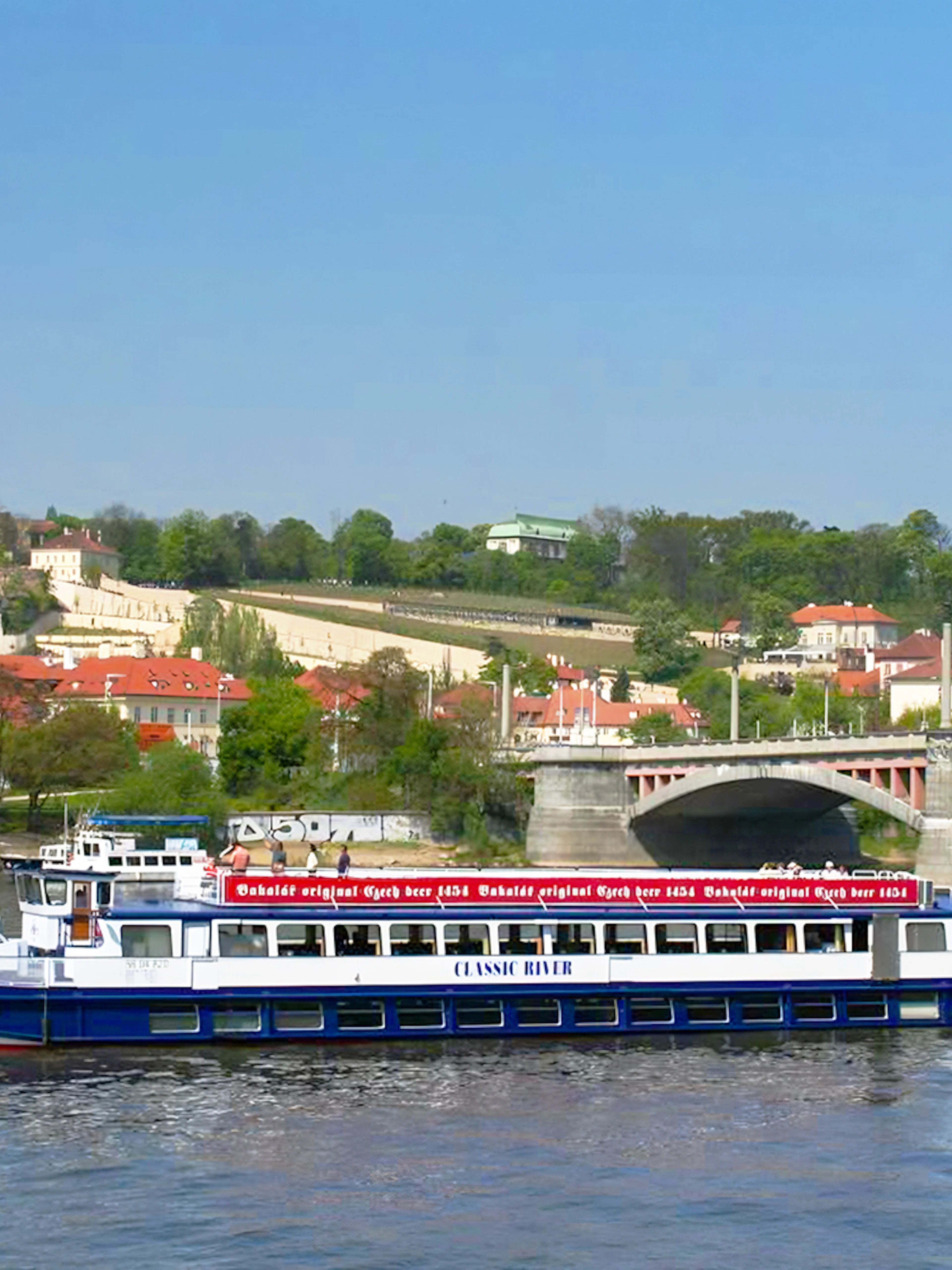 River cruise boat on Vltava River with Prague Castle in the background.