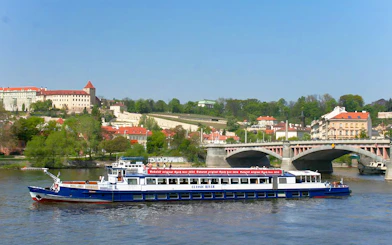 River cruise boat on Vltava River with Prague Castle in the background.