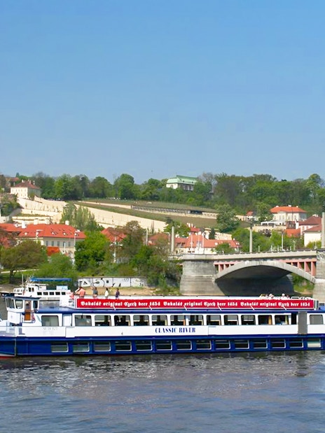 River cruise boat on Vltava River with Prague Castle in the background.