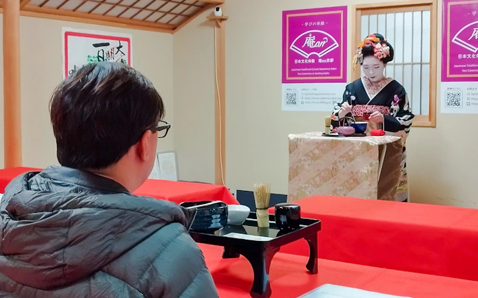 Tourist observing a Maiko performing a matcha tea ceremony in Kyoto.