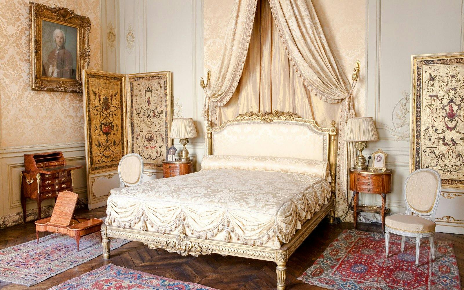 Elegant bedroom with ornate bed and antique furnishings at Jacquemart André Museum, Paris.