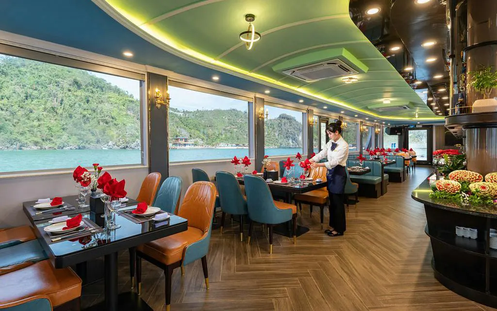 Dining area on La Casta Day Cruise with scenic Ha Long Bay views through large windows.