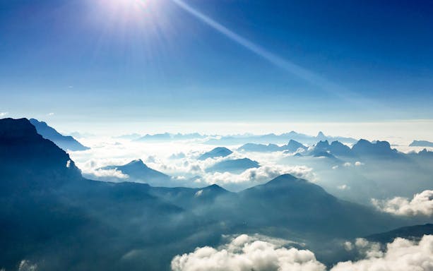 Aerial view of Bernese Seeland and Jura mountains with clouds and sunlight.